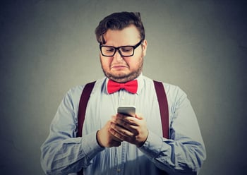 [Image] Disgusted businessman reading a smart phone. | State rules on entity names generally include restrictions on obscene, offensive and discriminatory words.