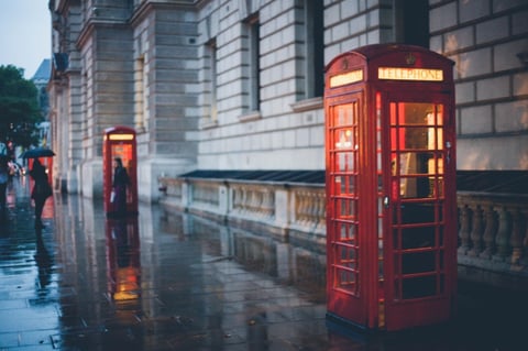 empty red phone booths during cloudy rainy day
