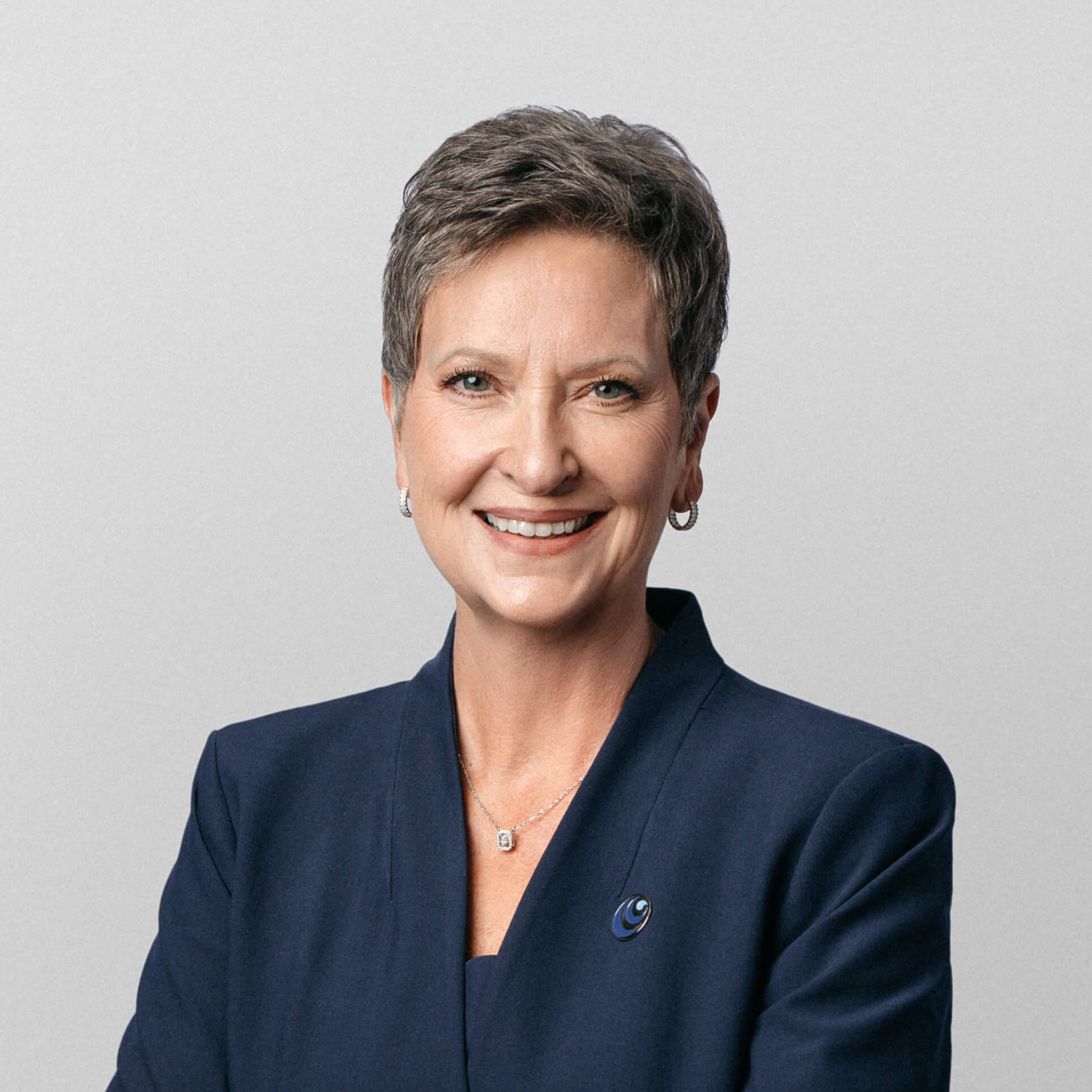 A smiling woman with short gray hair wearing a navy blue blazer.