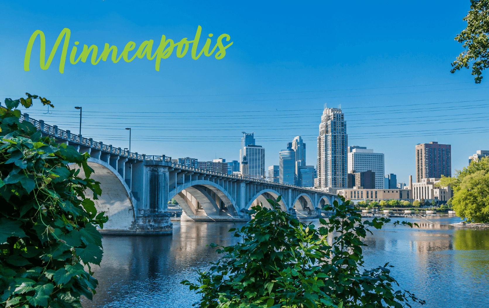 A view of the Minneapolis skyline with tall buildings, a stone arch bridge over the Mississippi River, and greenery in the foreground. "Minneapolis" is written in yellow script at the top left, highlighting the city’s charm during Legal week Conference season.